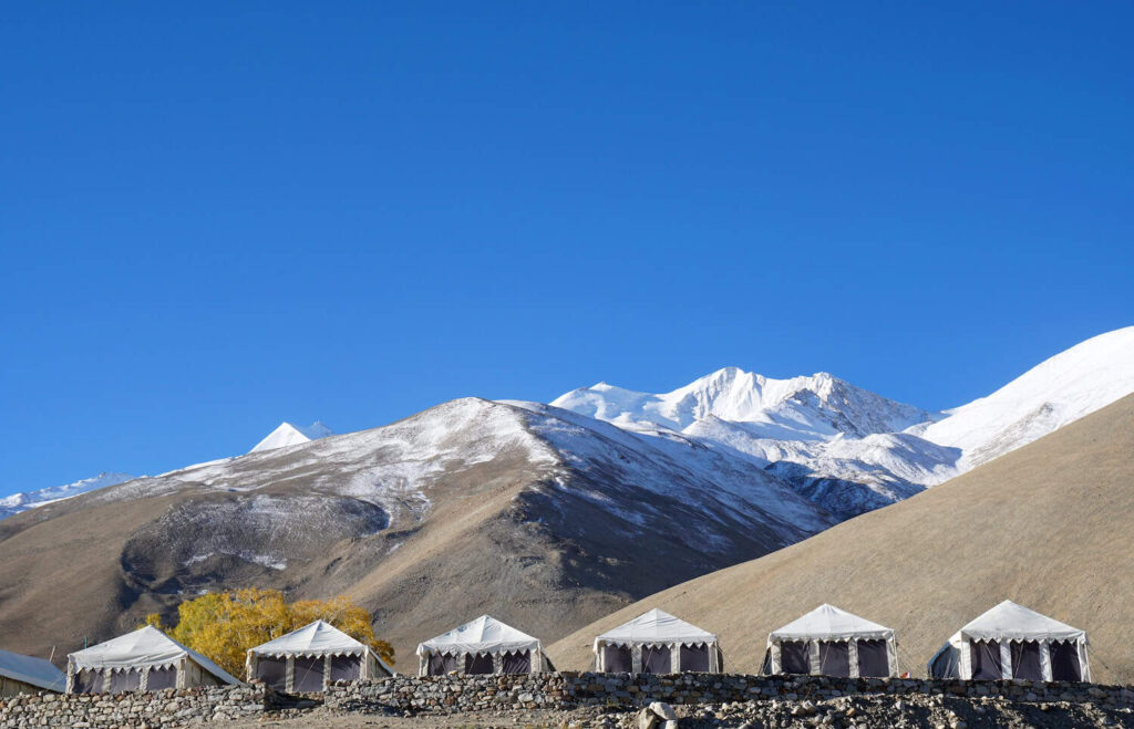 Scena naturale di un paesaggio di campeggio bianco e montagne innevate dell Himalaya sullo sfondo a Leh Ladakh Jammu e Kashmir India - Viaggi estremi e avventurosi...
